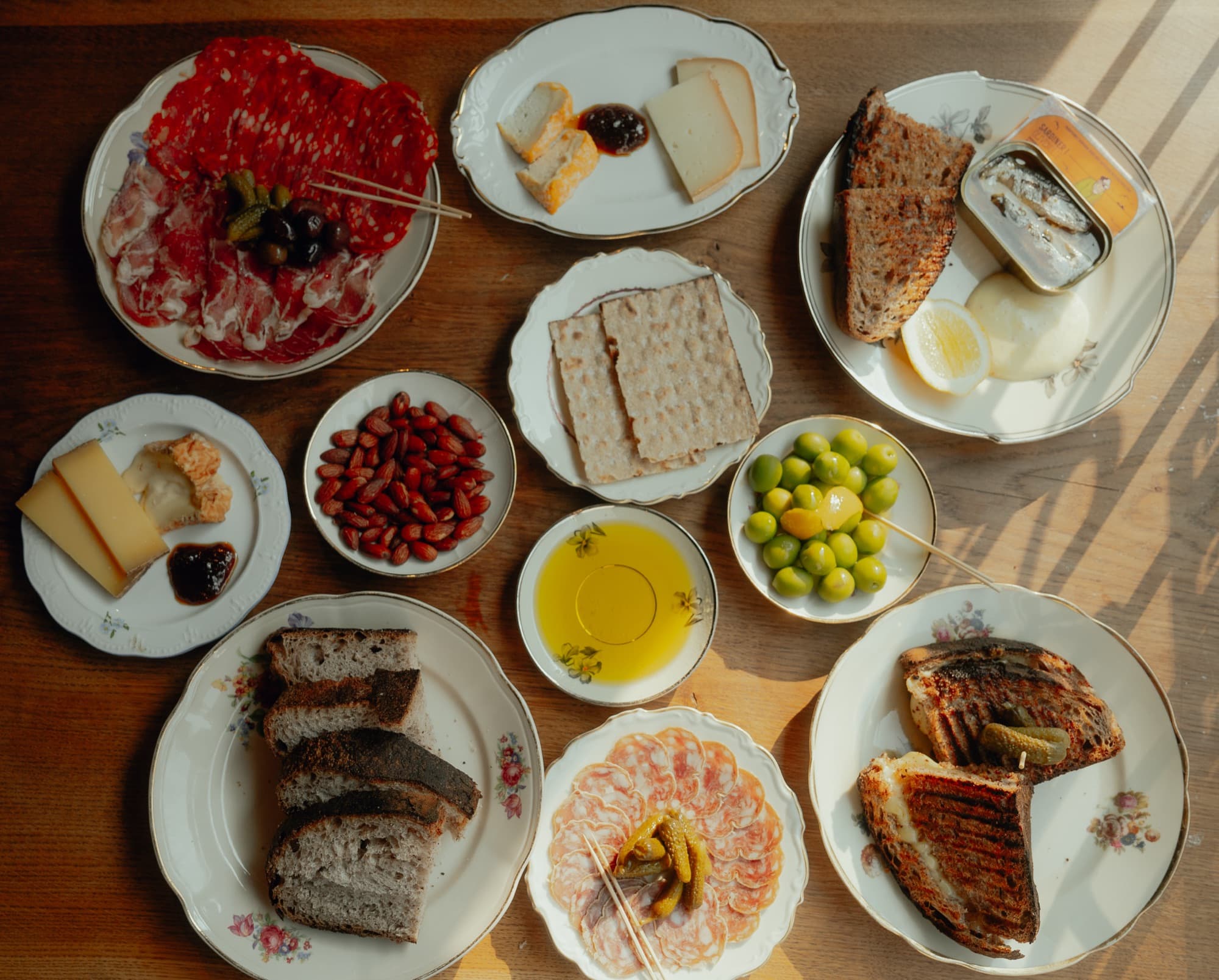 A table laid with cheese, charcuterie, olives, bread and a grilled sandwich