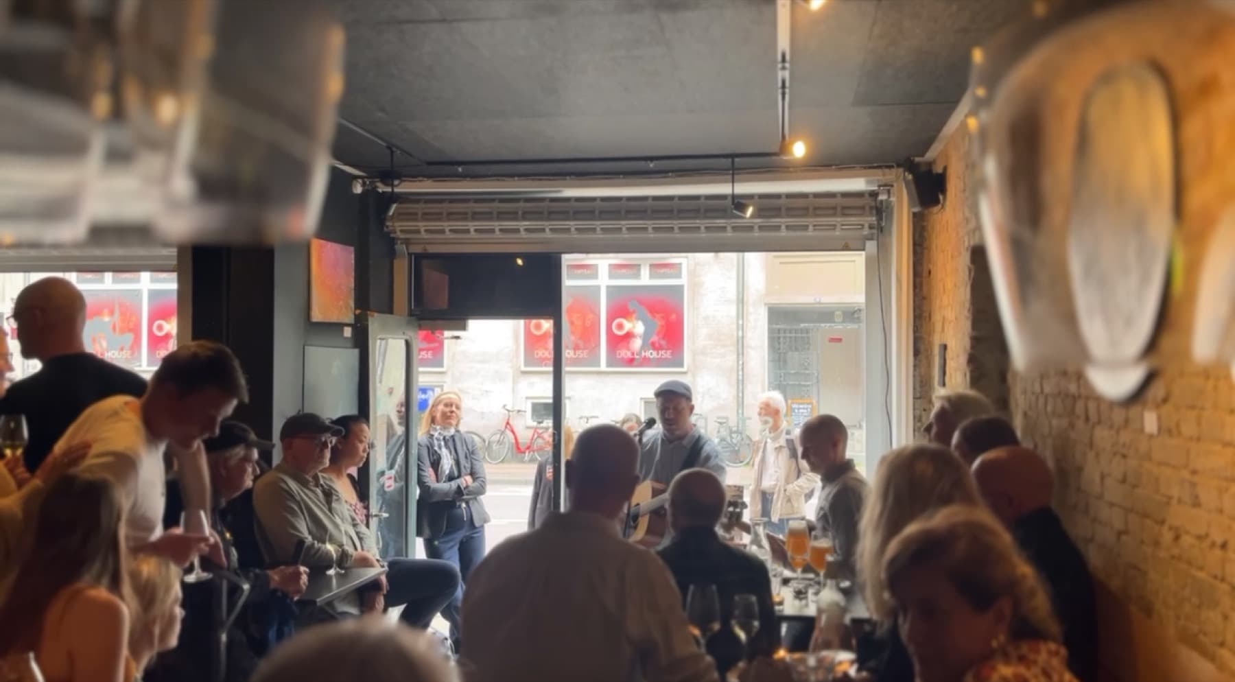 A packed room at Vesterhus with the audience close to the musician and the front open onto Istedgade
